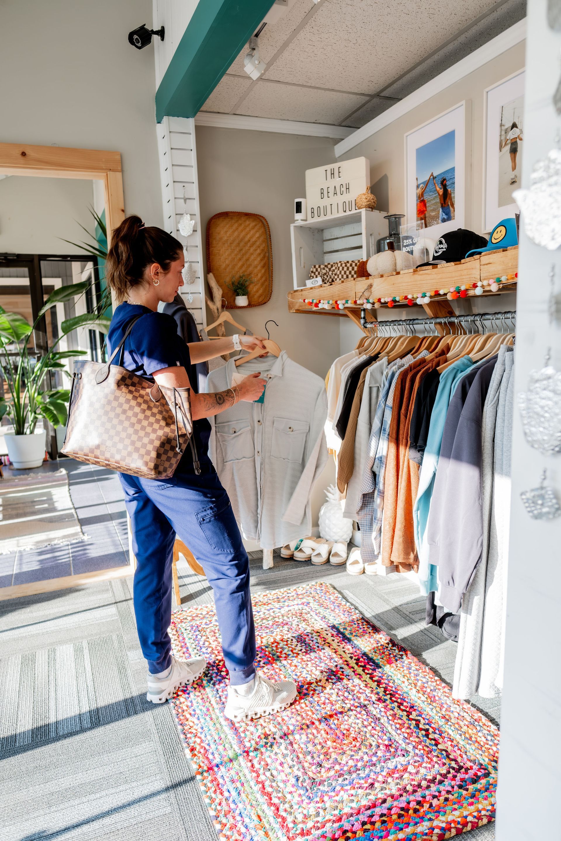 Woman shopping for clothes in a brightly lit boutique, browsing a rack of shirts. 