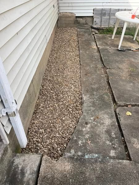 A sidewalk next to a house with gravel and a table.