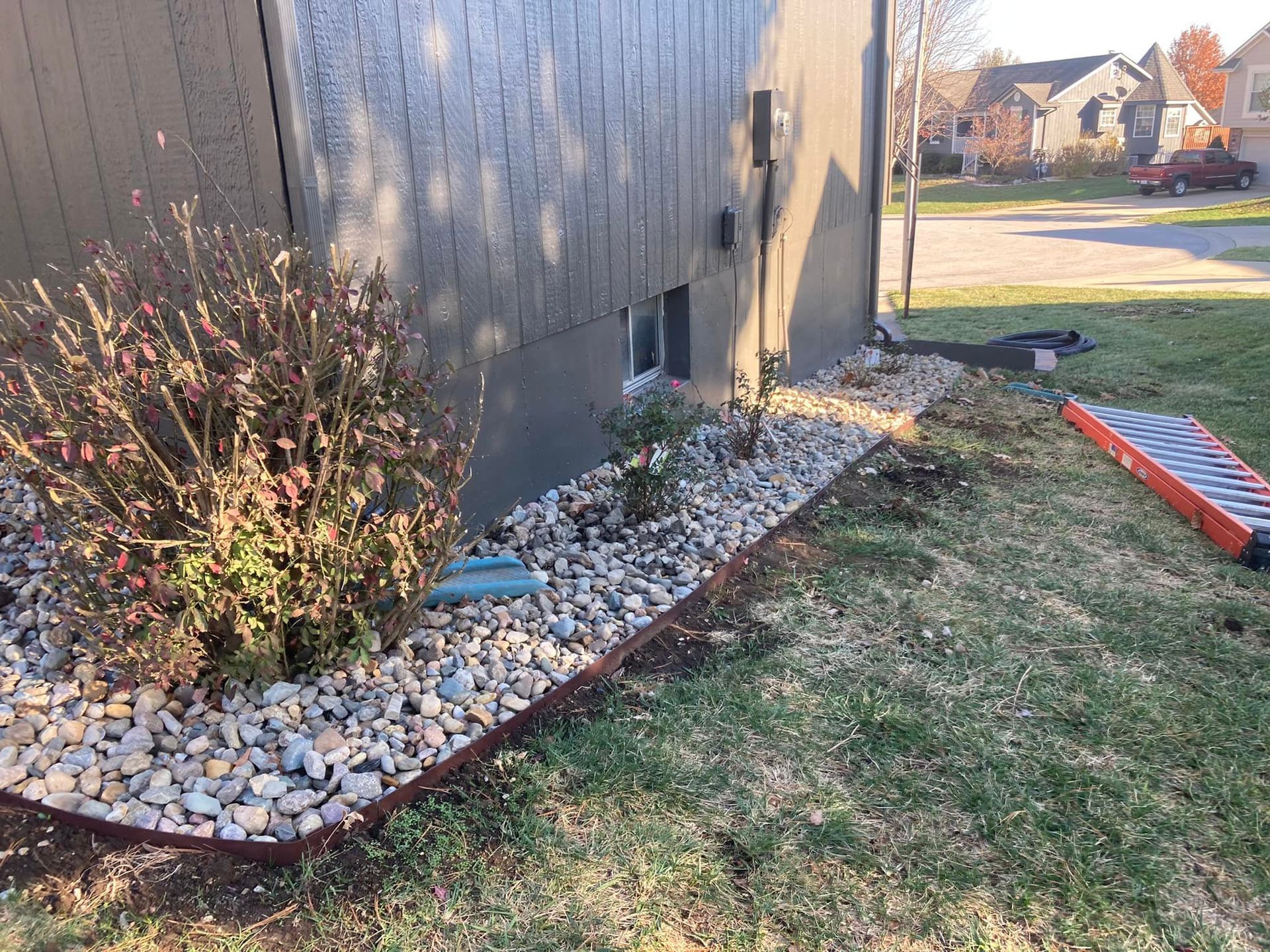 A lawn with rocks and a ladder in front of a house.