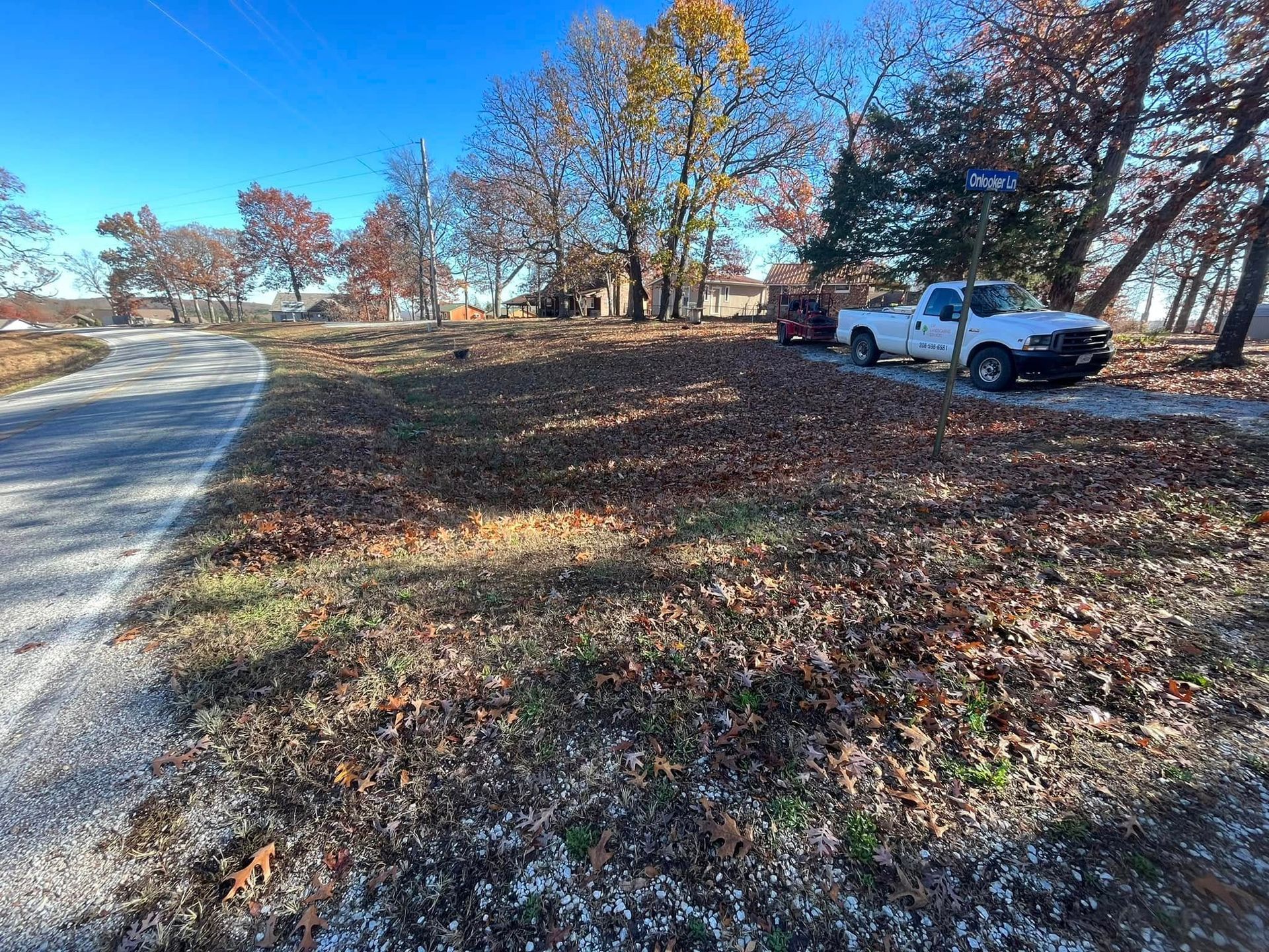A white truck is parked on the side of a dirt road.