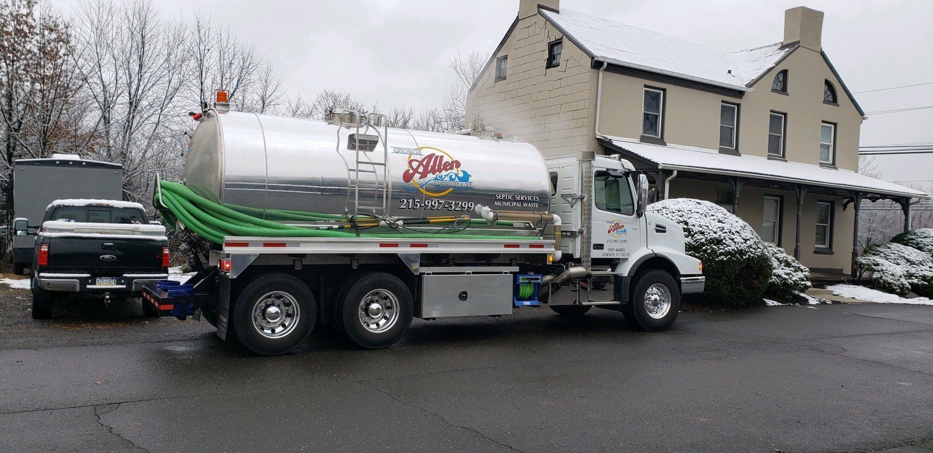 Tank truck parked beside a house in a snowy driveway.