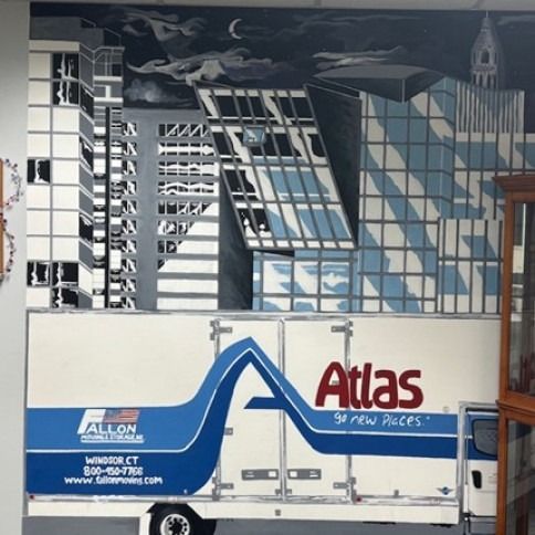 Mural of city skyline above a white and blue Atlas moving truck, under a dark sky with a crescent moon.