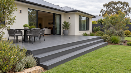 Design illustration of a grey composite deck with broad steps and a garden