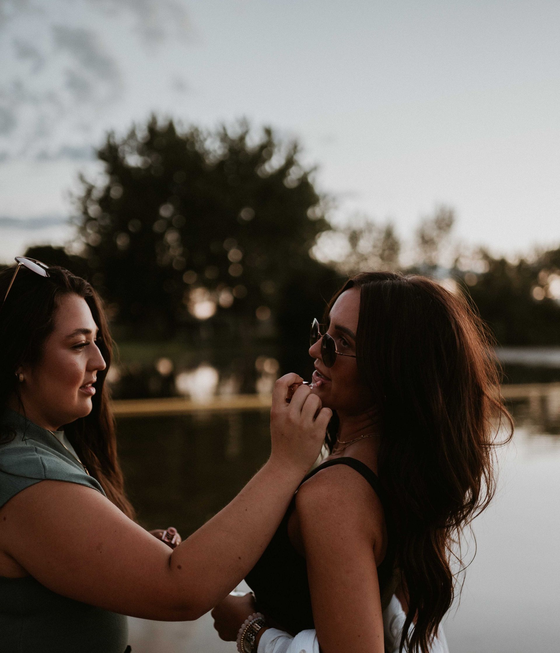 Two women are standing next to each other near a body of water.