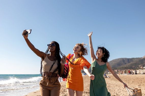 Three women are taking a selfie on the beach.