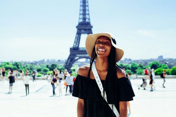 A woman wearing a hat is standing in front of the eiffel tower in paris.
