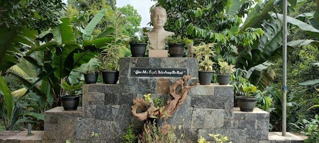 A statue of a man is surrounded by potted plants.