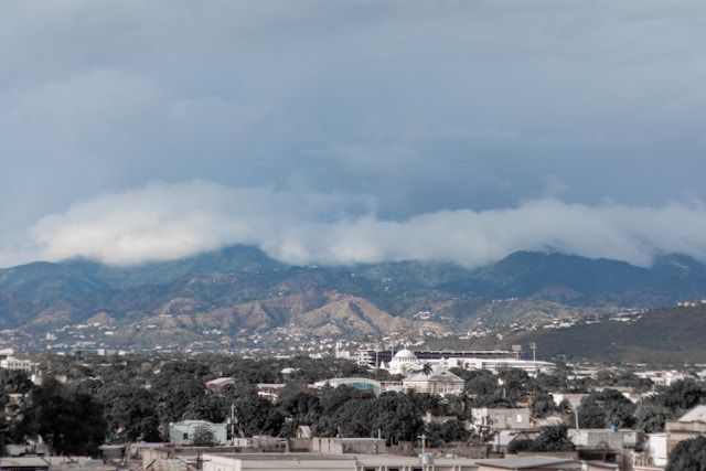 A city with mountains in the background and a cloudy sky