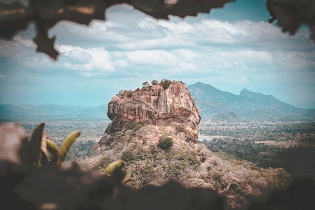 A large rock formation on top of a hill with mountains in the background.