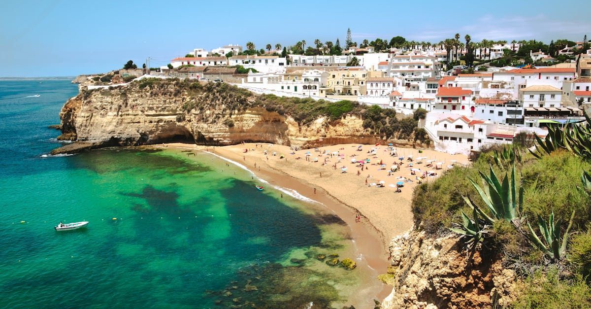 A beach on a cliff overlooking the ocean with a small town in the background.