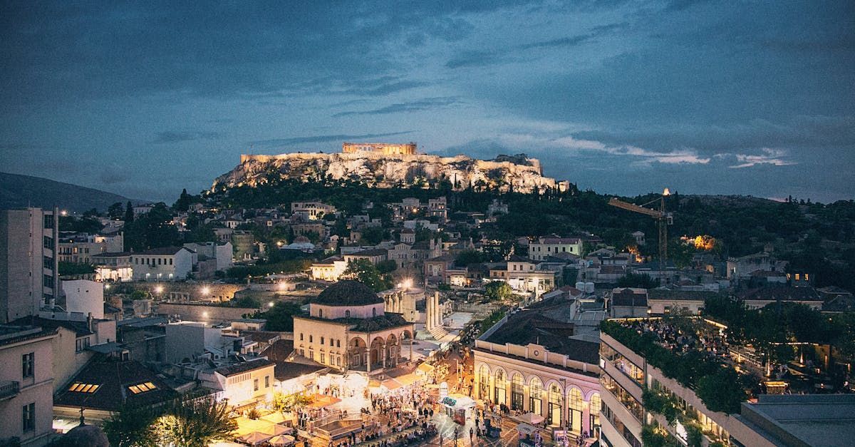 An aerial view of a city at night with a castle in the background.