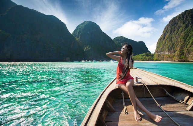 A woman in a red dress is sitting on a boat in the ocean.