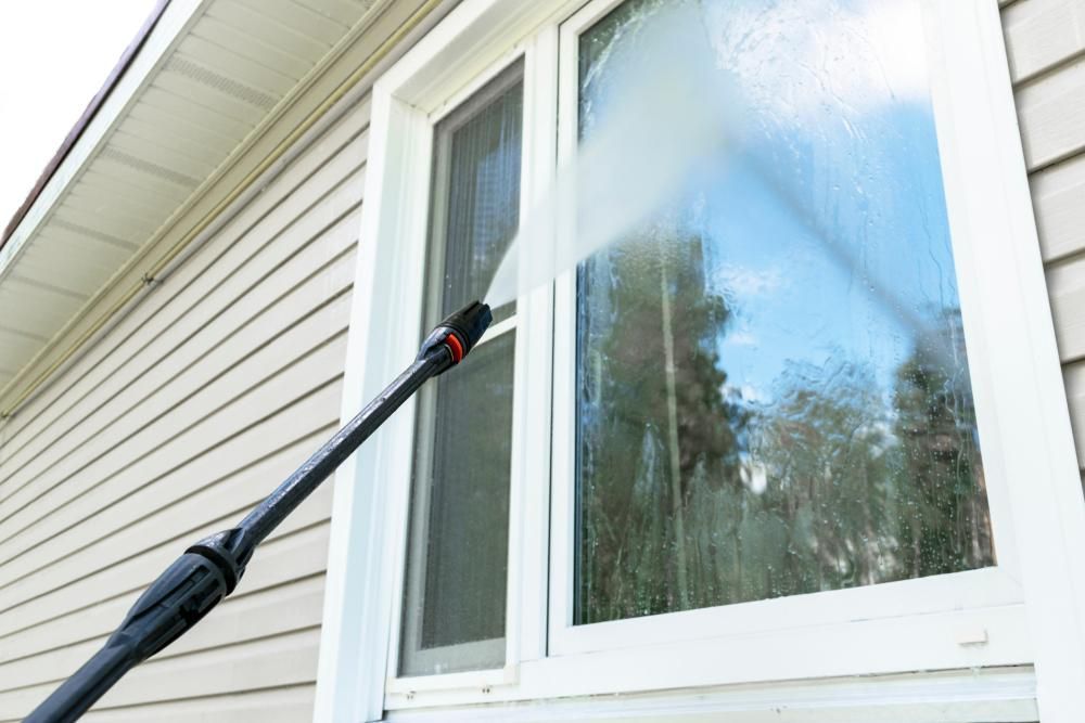 A Person Is Cleaning a Window — Professional Cleaning Company in Burrum Heads, QLD