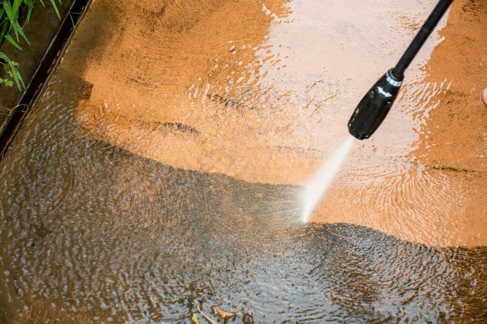 A Person Is Using a High-Pressure Washer — Professional Cleaning Company in Childers, QLD