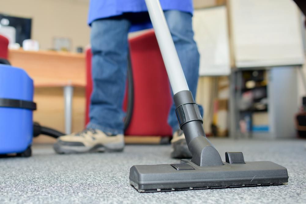 A Person Is Using a Vacuum Cleaner to Clean — Professional Cleaning Company in Burrum Heads, QLD