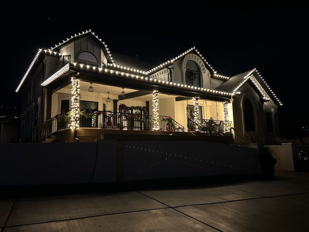 House outlined with white string lights at night, glowing warmly against the dark sky.