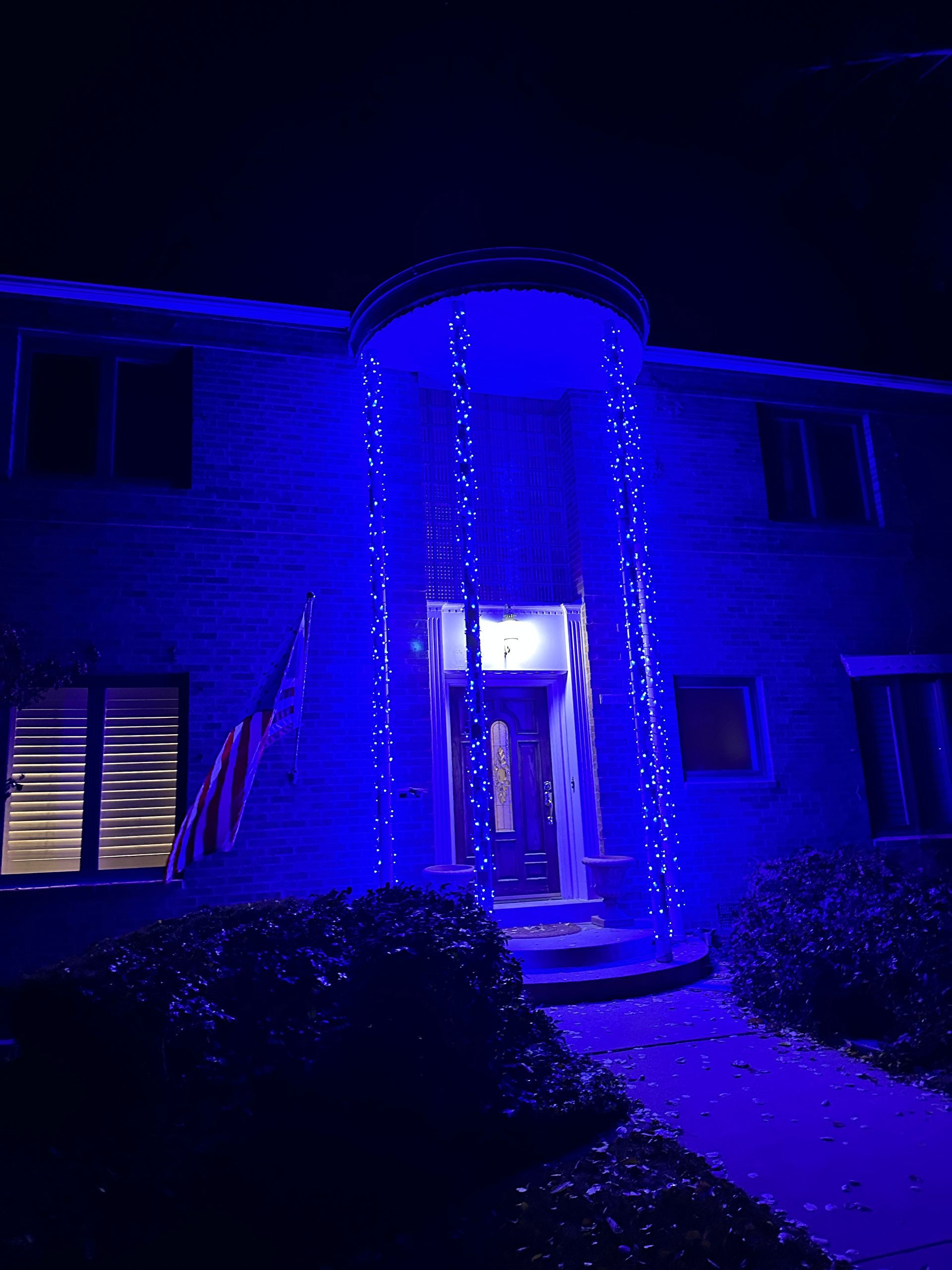 Blue-lit house exterior at night with illuminated doorway and steps