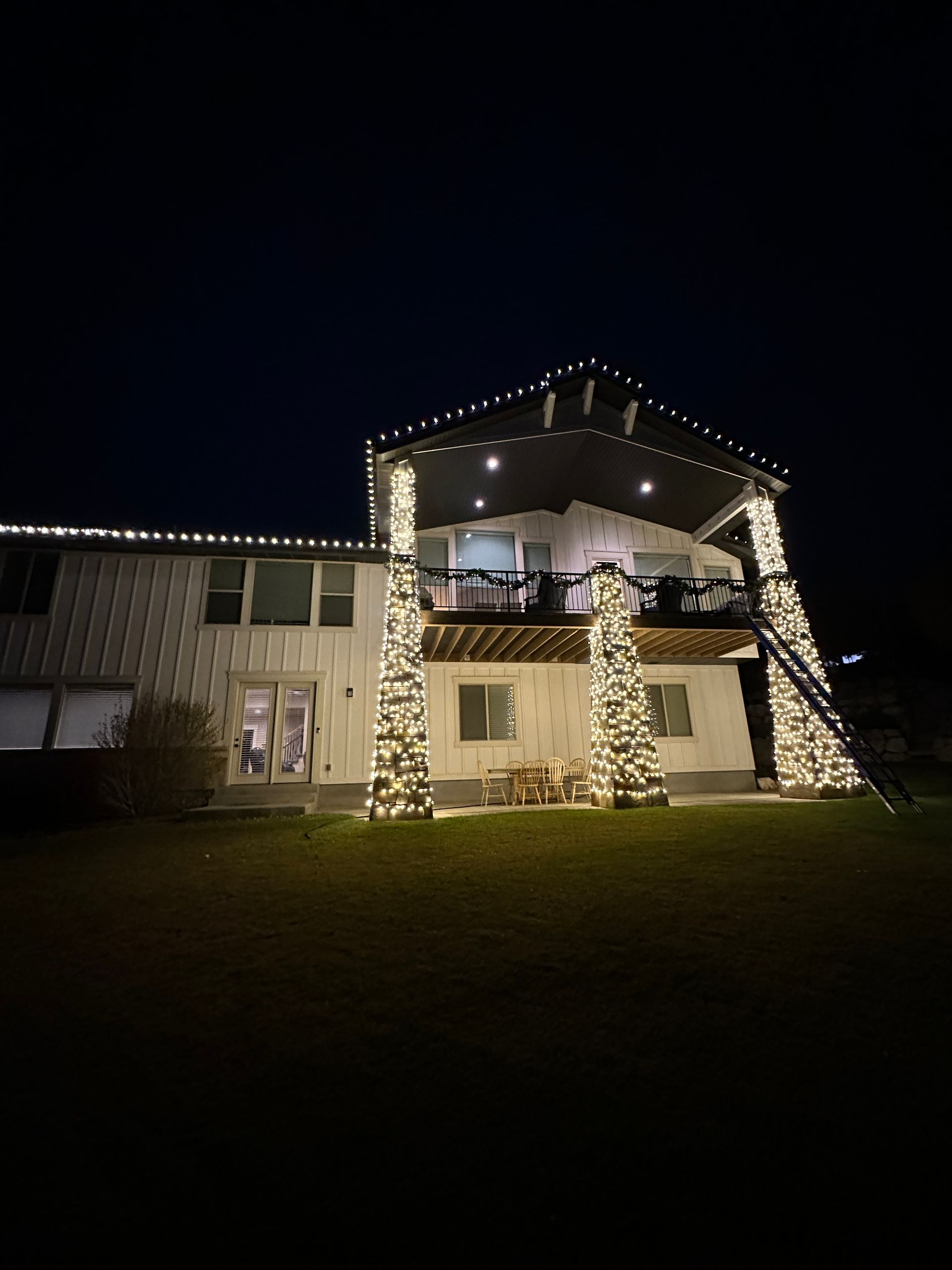 A house is decorated with christmas lights and trees at night.