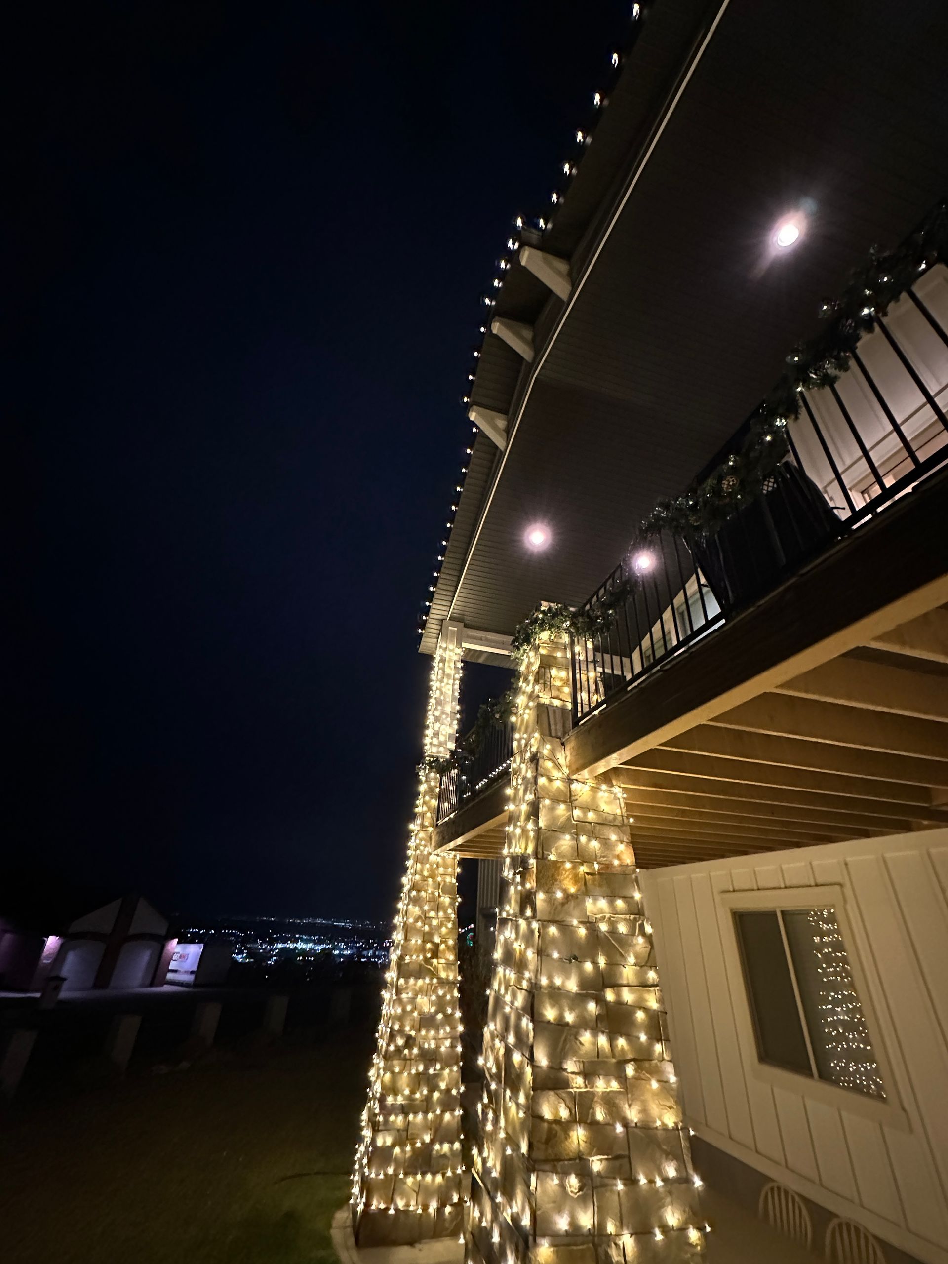 House exterior at night, lit with string lights wrapped around columns and roofline.