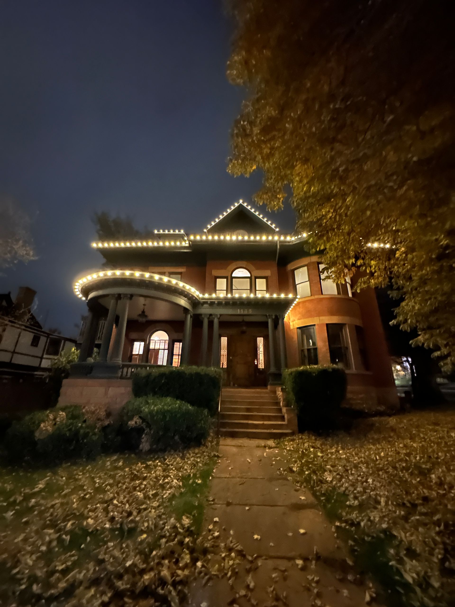 A house is decorated with christmas lights and pumpkins at night.