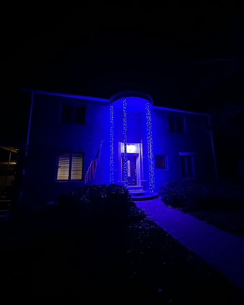 House with blue string lights around the entryway, glowing at night.