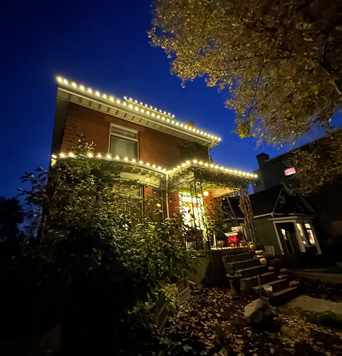 Brick house with white lights along roof edges at night, blue sky.