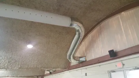 Ceiling vent duct beside a textured ceiling in a building interior