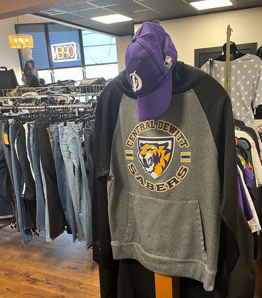 Clothing store rack with hoodies and jeans, including a gray and black hoodie in the foreground.