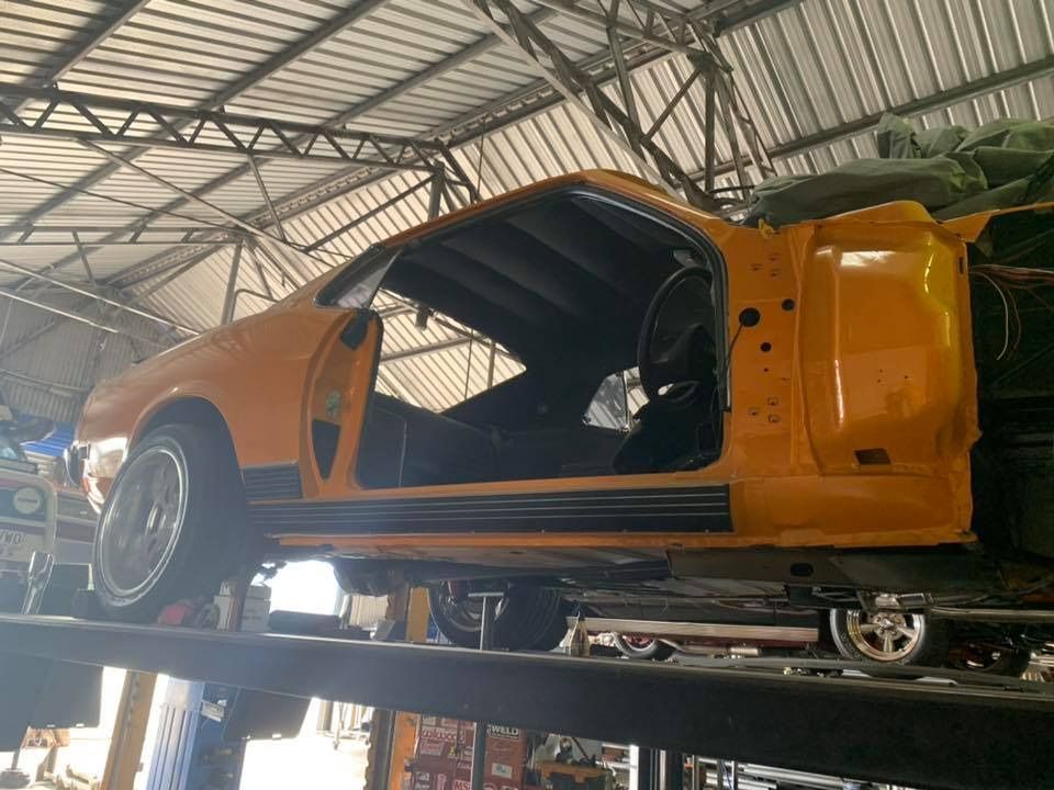 A Yellow Car Is Sitting On A Lift In A Garage — Hannam Street Mufflers and Mechanical In Bungalow, QLD