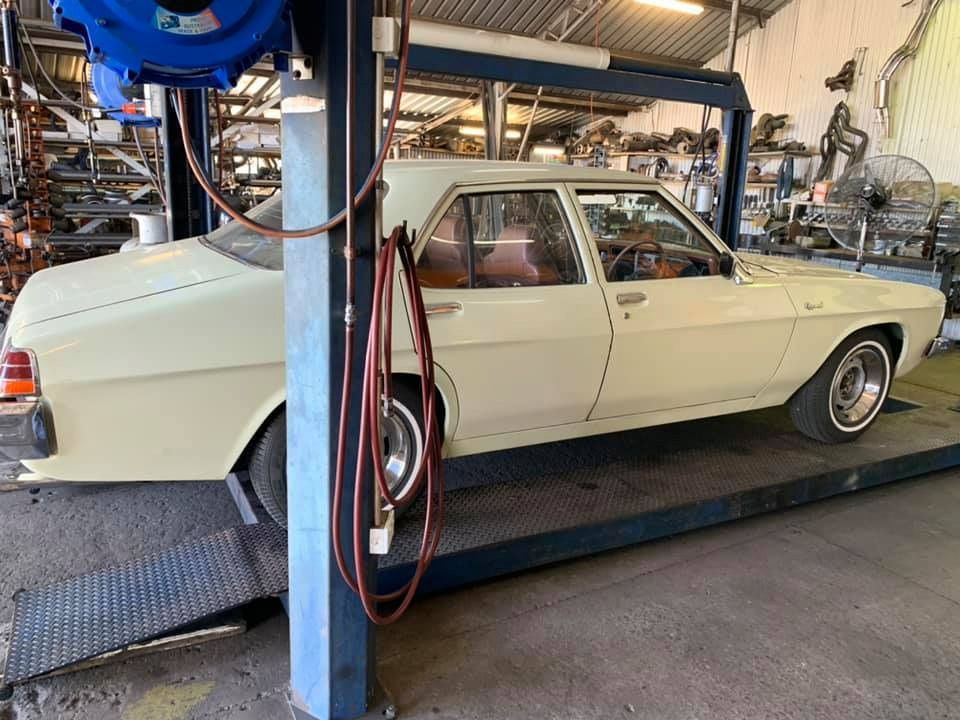 A White Car Is Parked On A Lift In A Garage — Hannam Street Mufflers and Mechanical In Bungalow, QLD