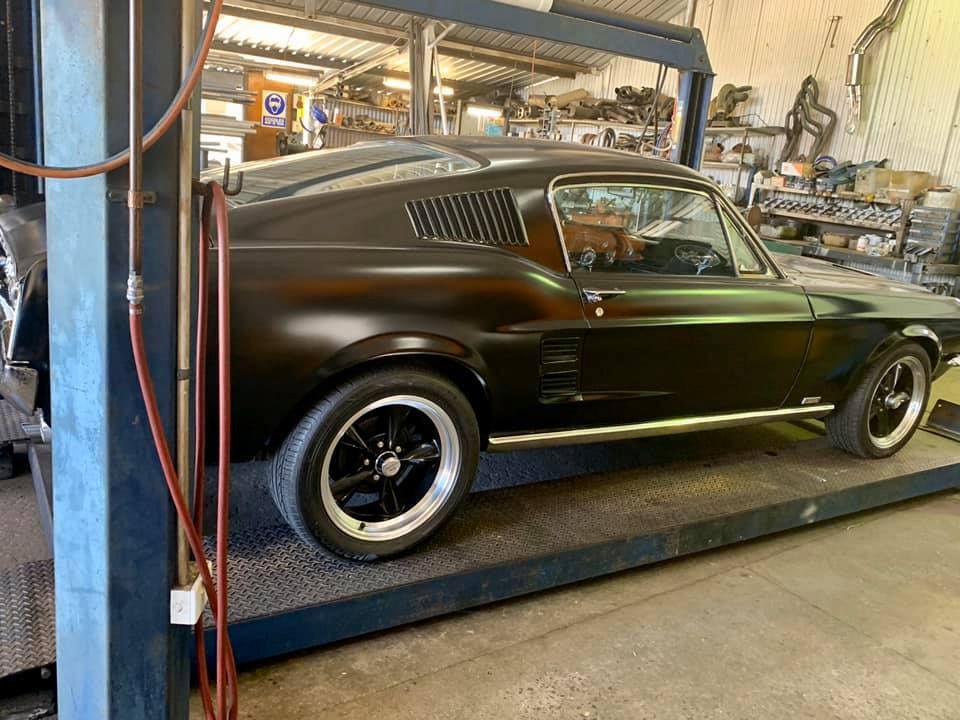 A Black Mustang Is Parked In A Garage On A Lift — Hannam Street Mufflers and Mechanical In Bungalow, QLD