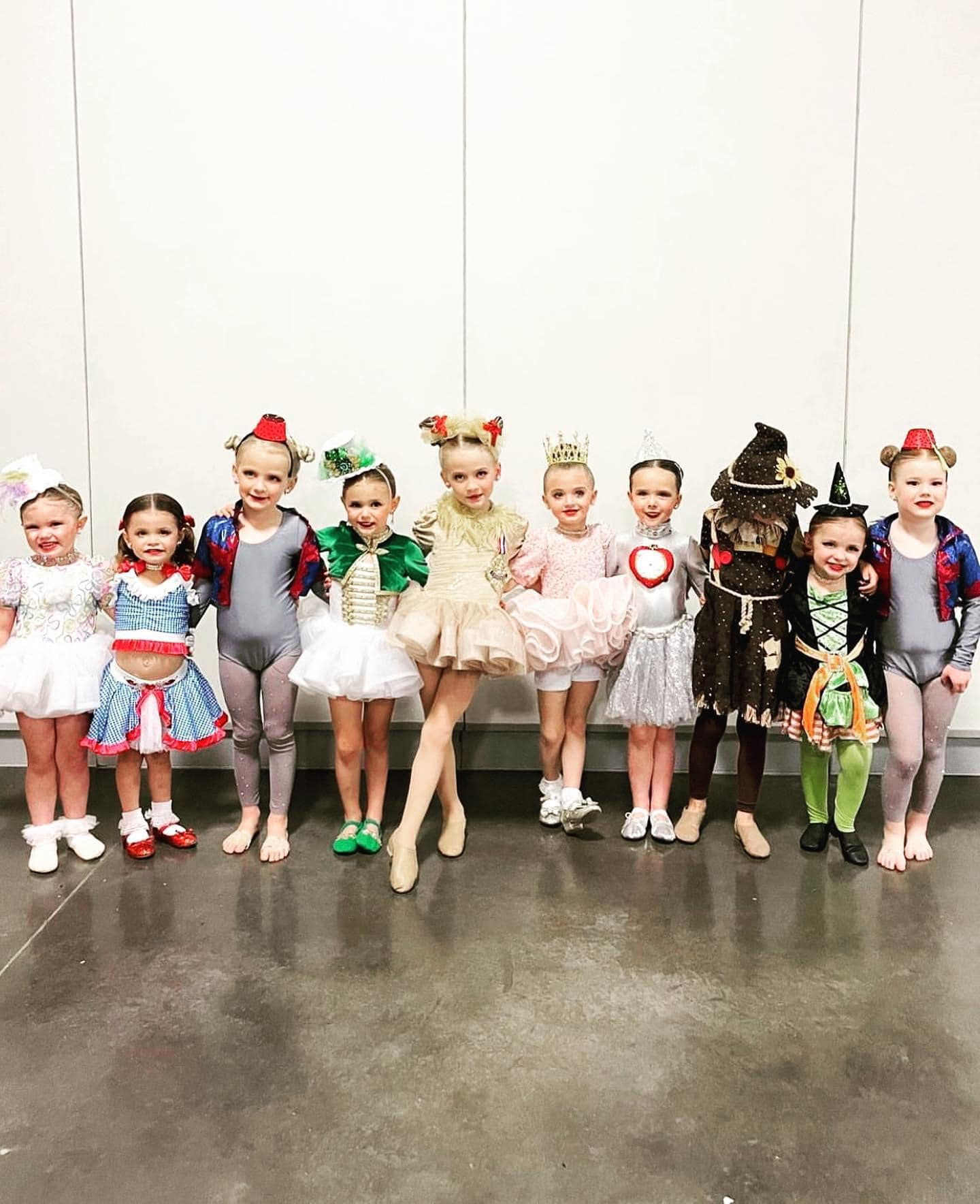 A group of young girls in costumes are posing for a picture.
