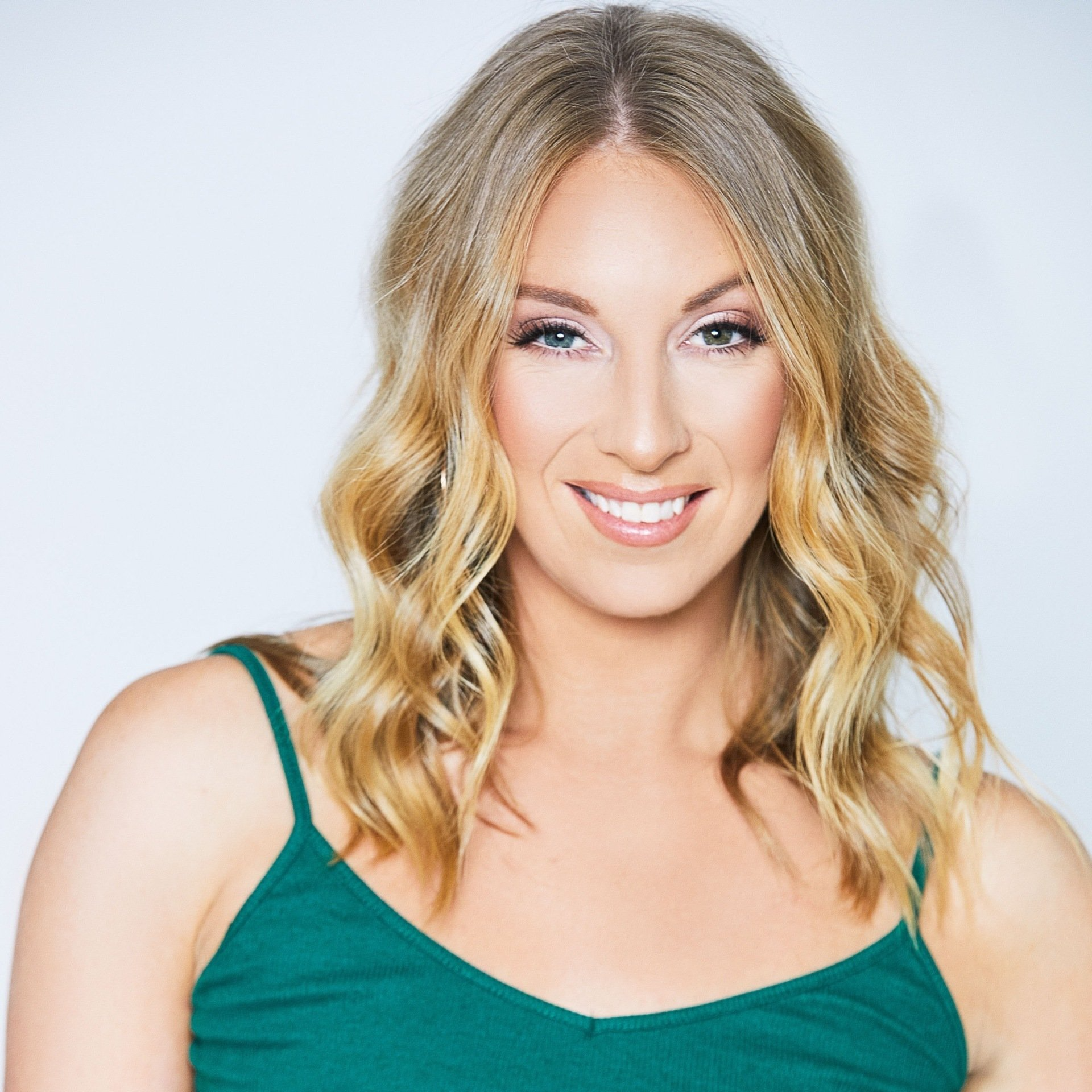 A woman in a green tank top smiles for the camera