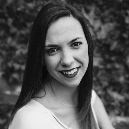 A woman with long hair is smiling in a black and white photo.