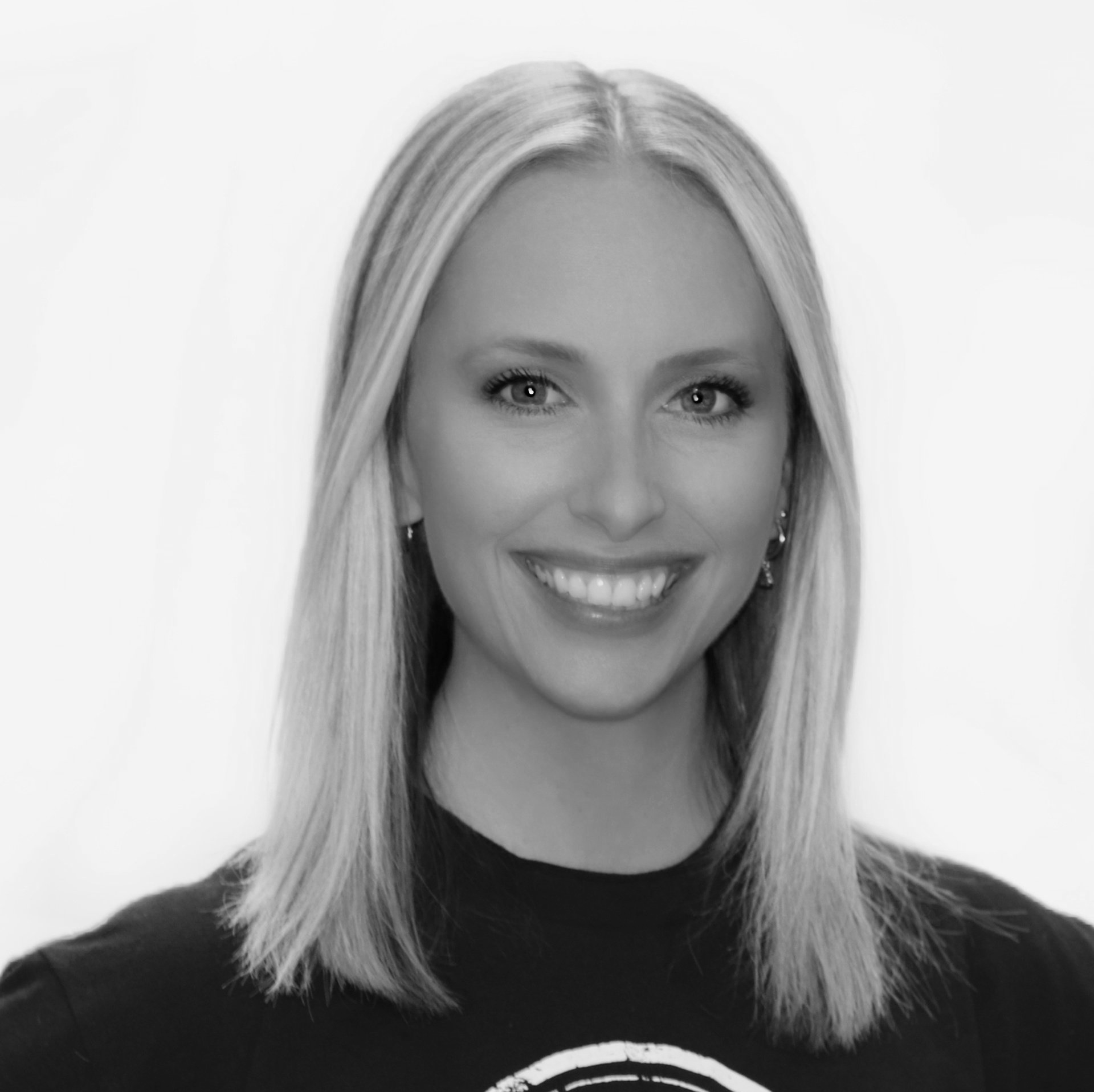 A black and white photo of a woman wearing a black shirt and smiling.