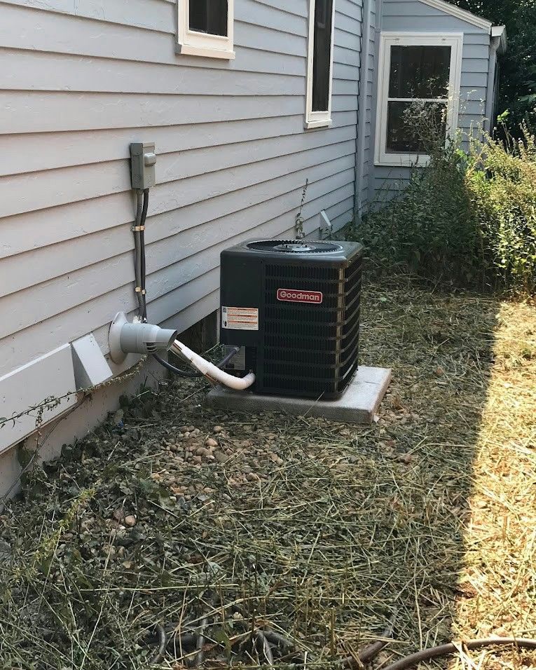 A beige air conditioning unit mounted on a textured wall above a wooden deck.