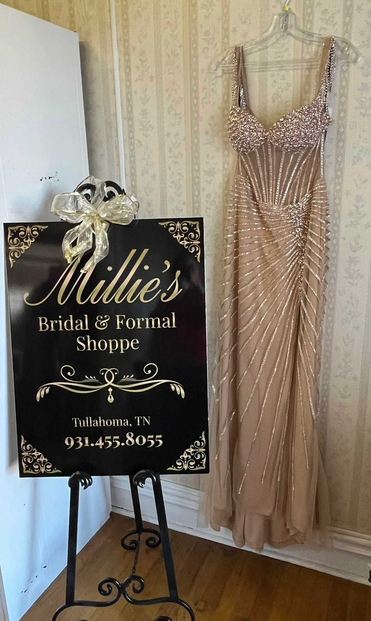 Wedding dress boutique sign beside a sparkly blush gown on a hanger