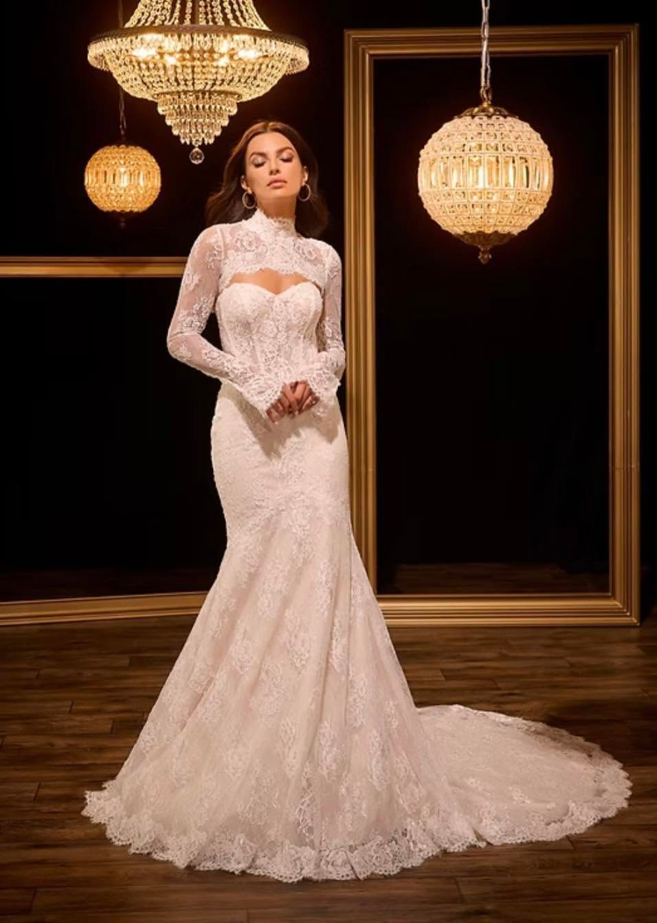 Woman in a white lace gown posing under chandeliers on a dark stage
