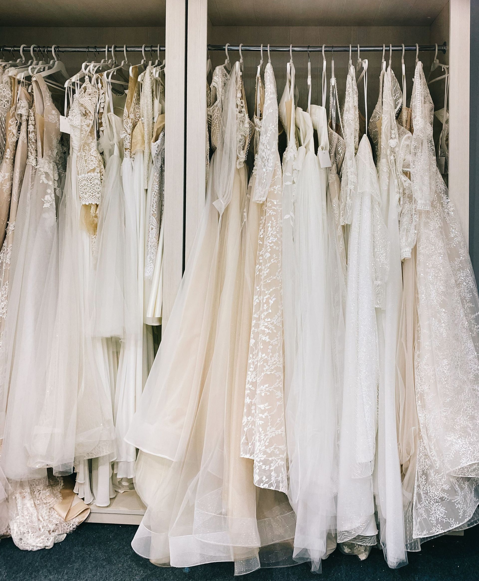 White wedding dresses hanging on racks in a bridal shop