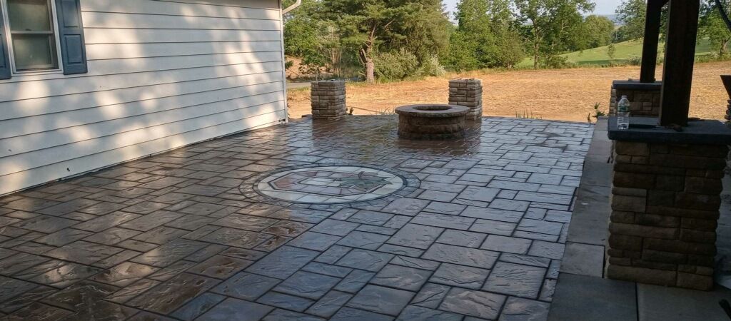 Brick patio with a white house wall, outdoor furniture, and a fire pit in a sunny backyard