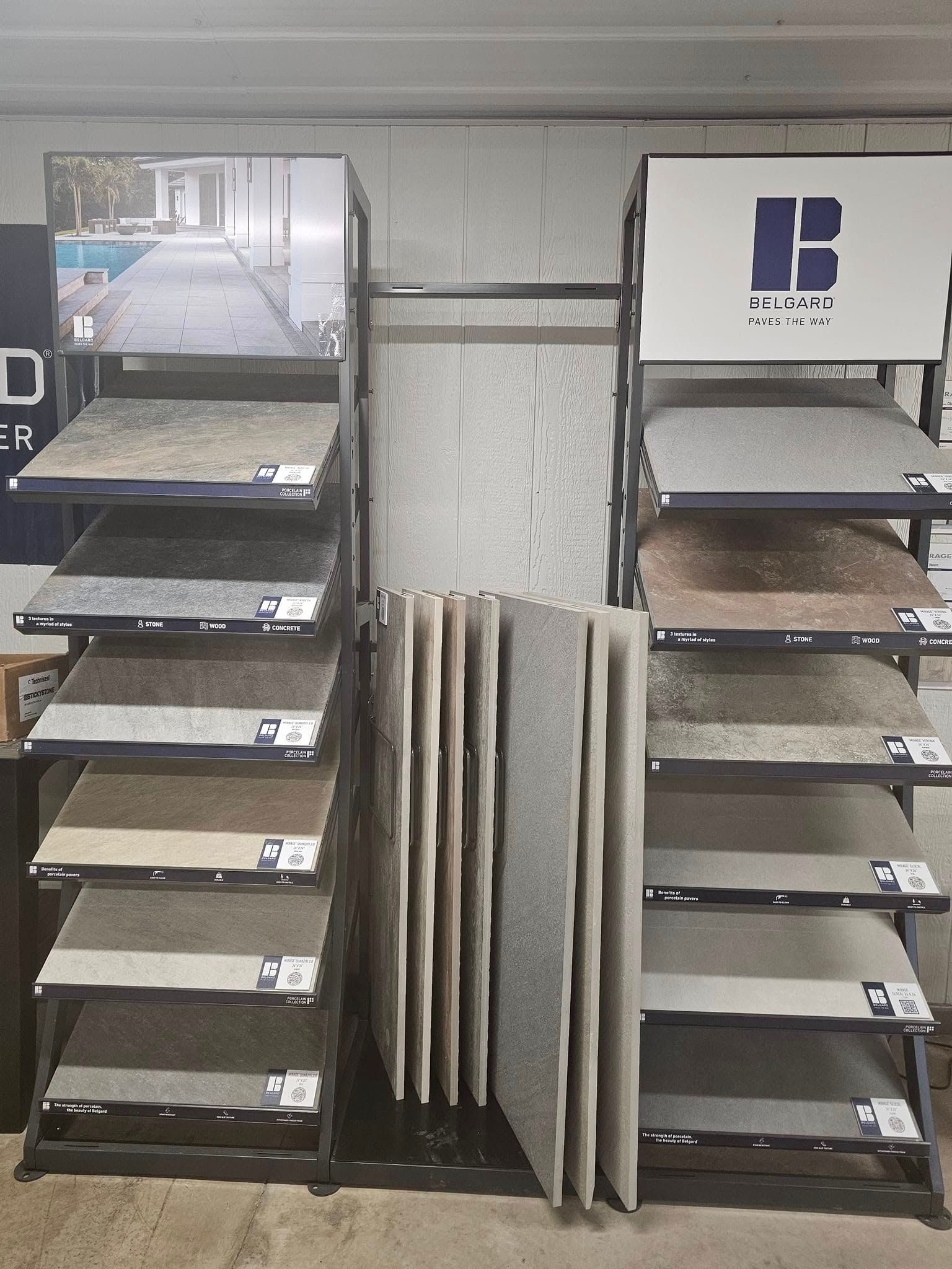 Display racks with several dark sample boards and a central stack of white panels against a wall.