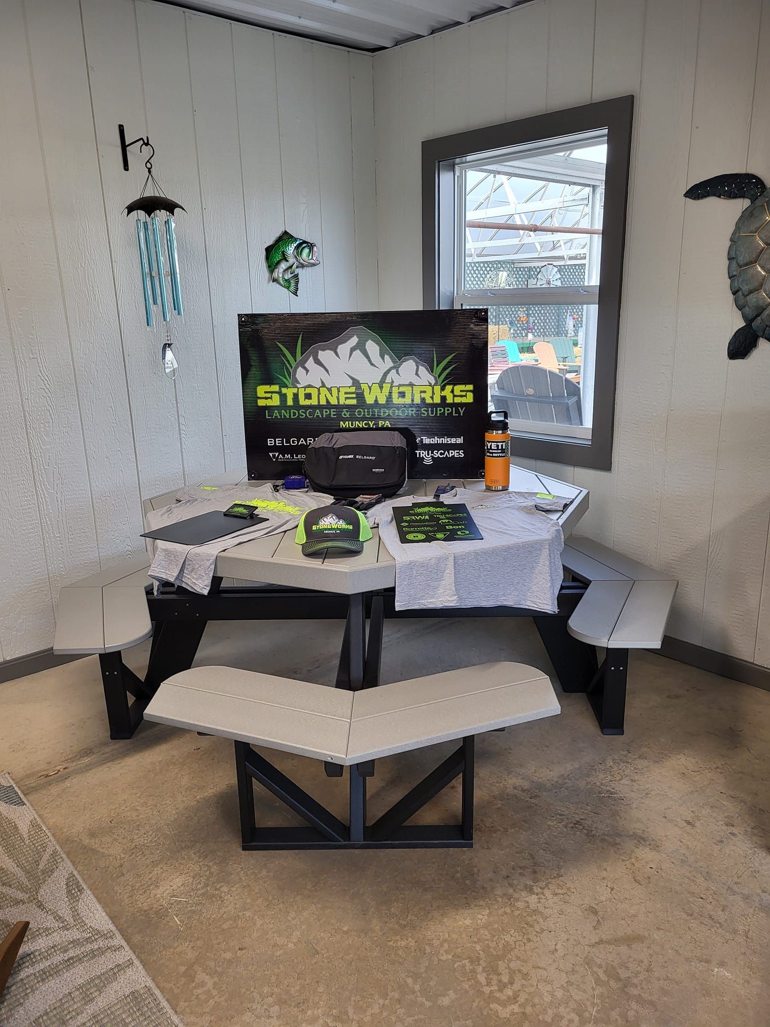 Small dining nook with a TV, game console, and controller on a white table, beside a window.
