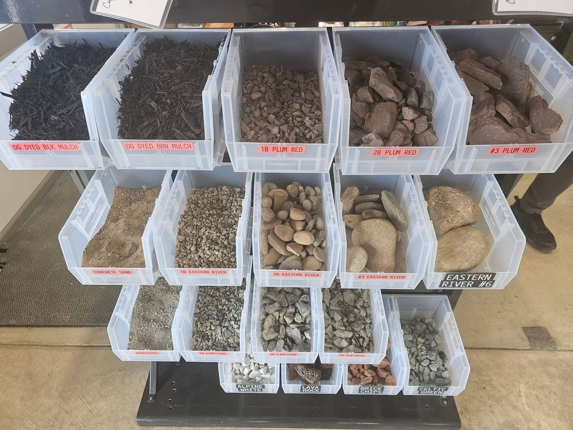 Assorted rocks, gravel, and soil samples sorted into labeled plastic bins on a table.