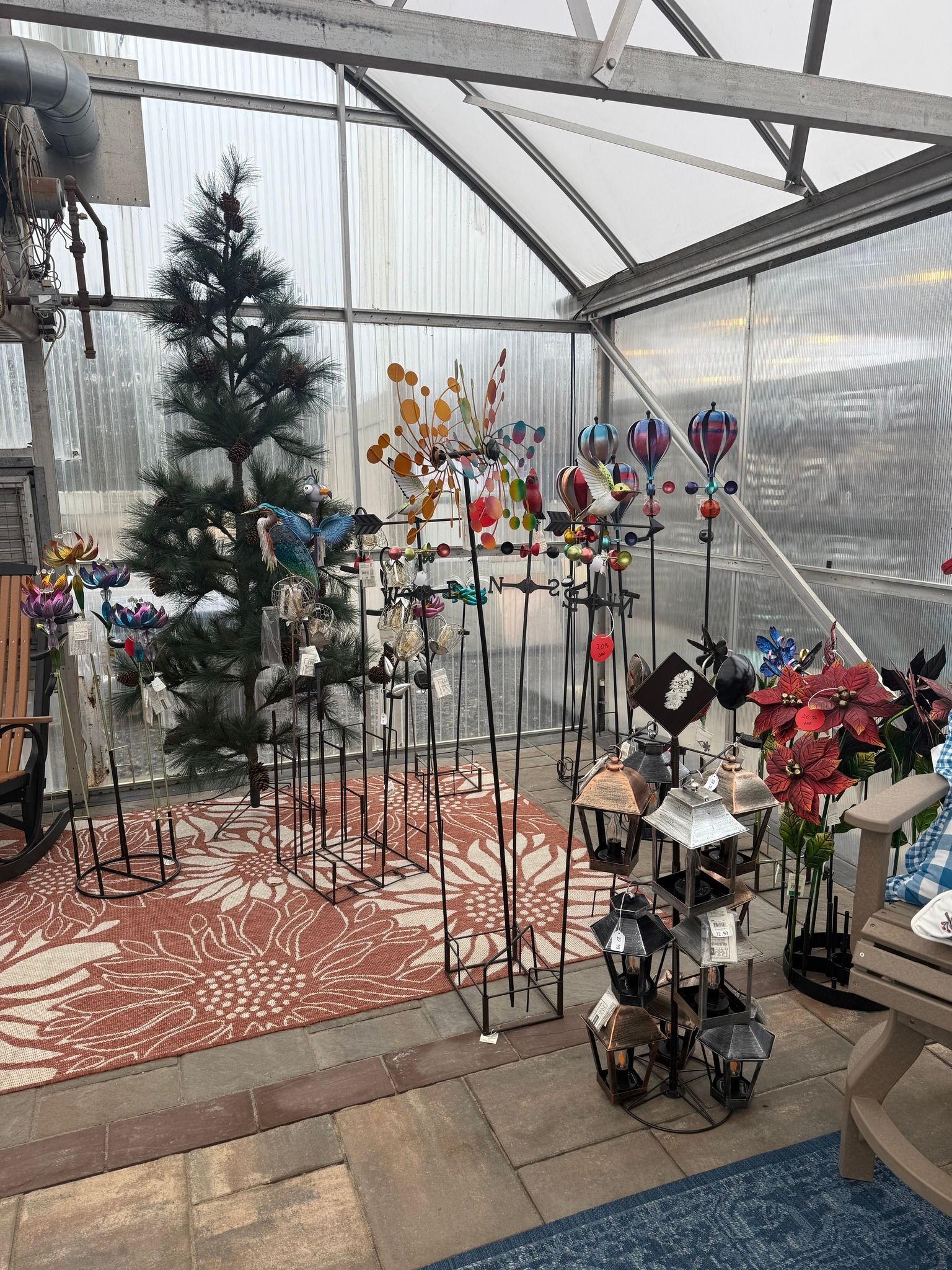 Indoor garden shop with colorful metal flower and wind spinner displays on a patterned rug
