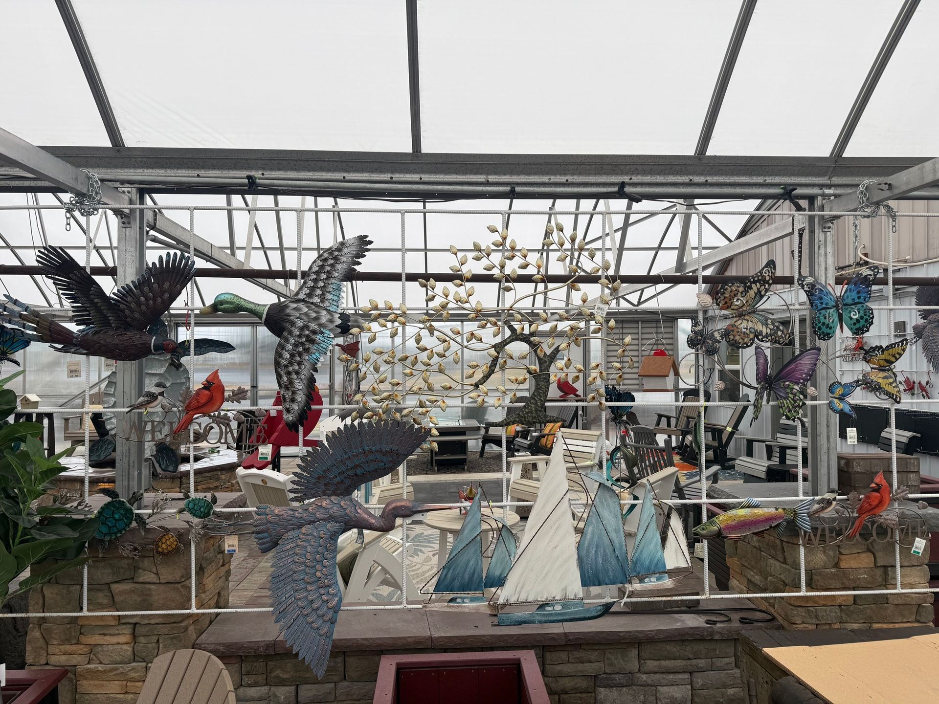 Hanging metal bird sculptures and mosaic fish in a greenhouse-like art display
