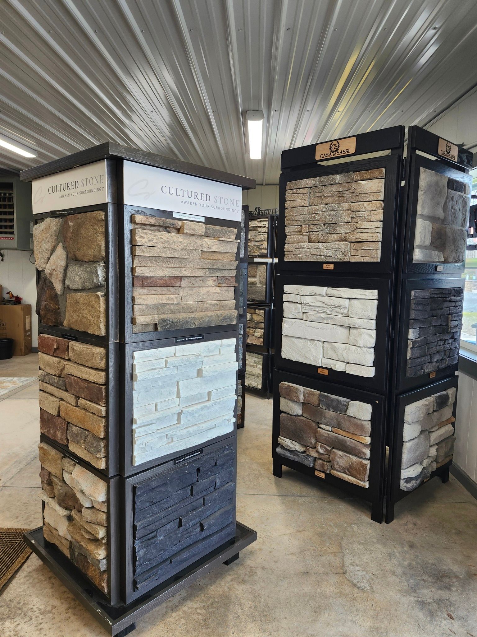 Stone veneer displays in a showroom with black frames and stacked sample panels.