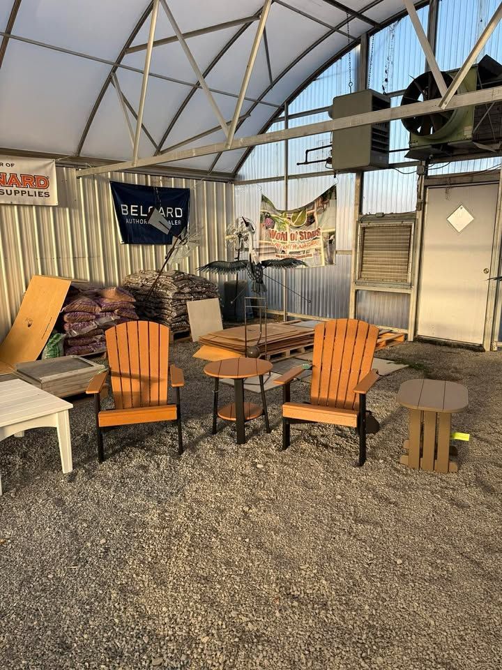 Outdoor patio with metal canopy, two wooden chairs, small tables, and gravel ground.