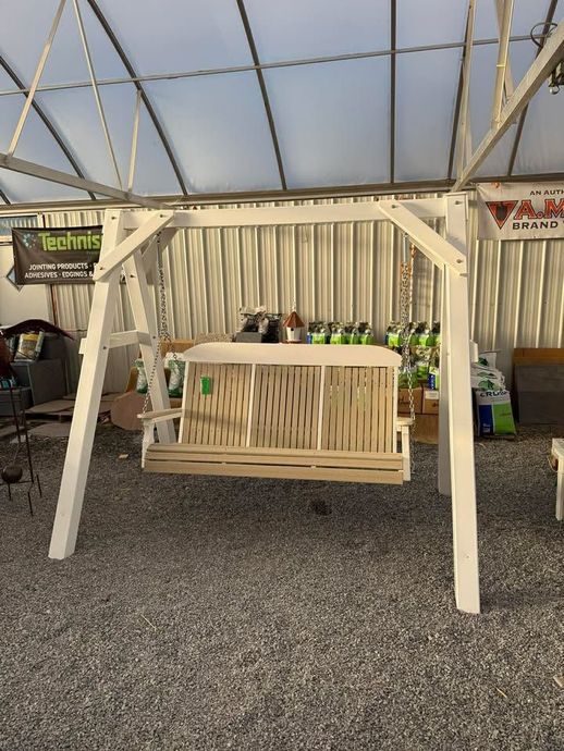 White porch swing in a tented booth with green bottles and a gravel floor beneath it