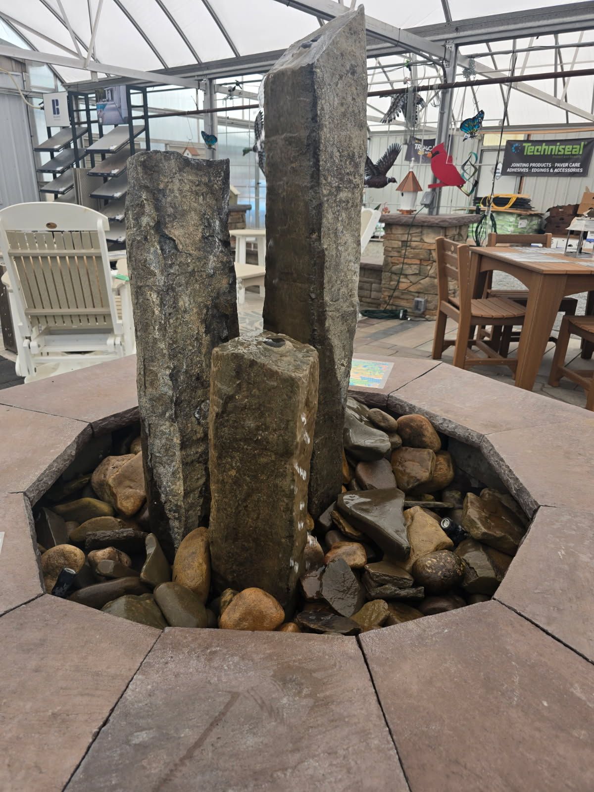 Stone fountain with tall rock pillars in a greenhouse-style indoor seating area