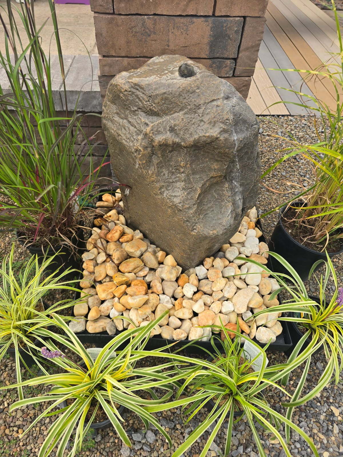 Decorative gray stone surrounded by pebbles and small plants in a landscaped garden bed